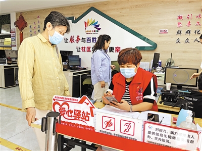 8月31日，社區(qū)工作人員幫助老年居民在手機(jī)上辦理業(yè)務(wù)。      本報(bào)記者 毛雪皎 攝