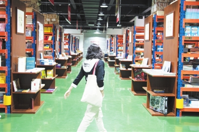 5月5日，在賀蘭縣德勝工業(yè)園區(qū)的新華書店德勝倉賣場，一位市民在書架間穿梭。該賣場由占地面積1600平方米的書店倉庫轉(zhuǎn)型而來，人們可以推著購物車，像在超市一樣穿梭在書架間選購圖書。賣場書籍總量超過10萬冊，還著重營造閱讀環(huán)境，設(shè)置了閱讀區(qū)、文創(chuàng)區(qū)等區(qū)域。    本報記者  季正  攝