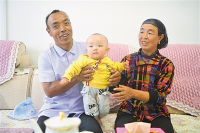 <p>　　劉克瑞（左）和妻子在客廳中陪孫子玩耍。　均本報記者　馬楠　攝</p>